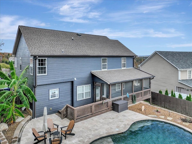 rear view of house featuring a fenced in pool, a sunroom, and a patio