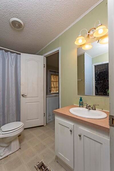 bathroom featuring crown molding, vanity, a textured ceiling, and toilet