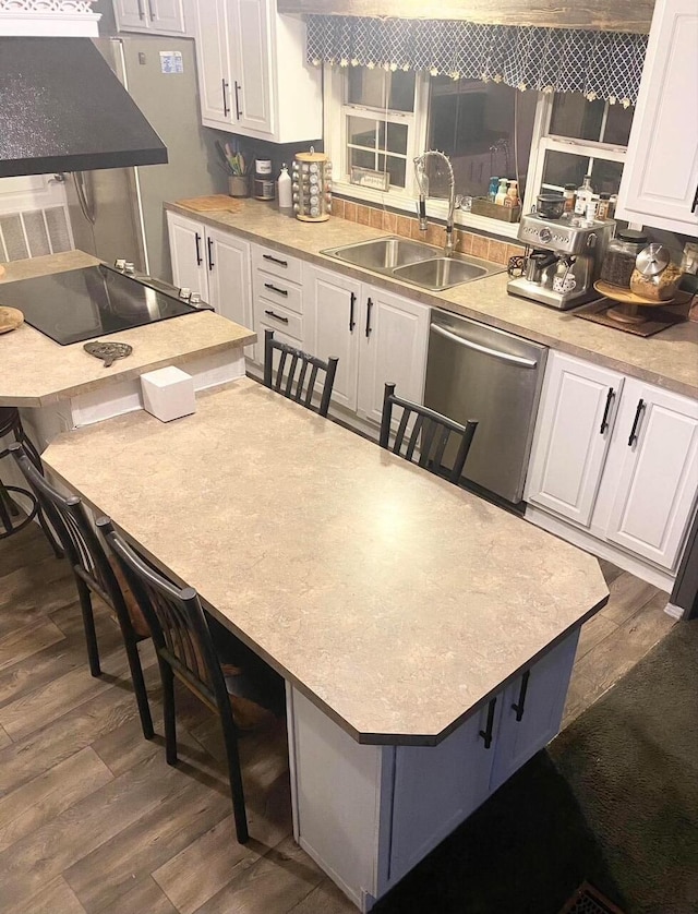 kitchen featuring stainless steel dishwasher, a breakfast bar, white cabinets, and sink