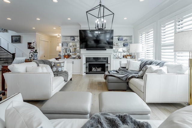 living room featuring crown molding, light hardwood / wood-style flooring, and a notable chandelier