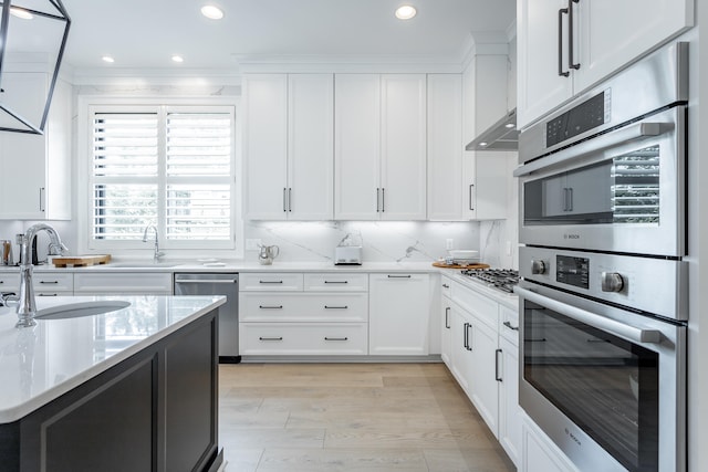 kitchen with sink, decorative backsplash, light wood-type flooring, white cabinetry, and stainless steel appliances