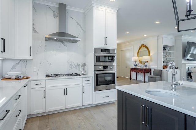 kitchen featuring wall chimney range hood, decorative backsplash, ornamental molding, light hardwood / wood-style floors, and white cabinetry