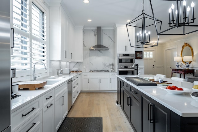 kitchen featuring white cabinetry, a center island, sink, wall chimney exhaust hood, and decorative light fixtures