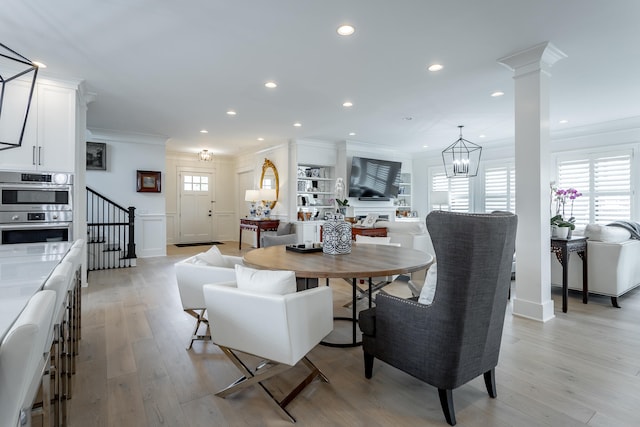 dining area with ornamental molding, a notable chandelier, and light wood-type flooring