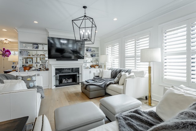 living room featuring a chandelier, light wood-type flooring, and ornamental molding