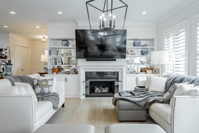 living room with ornamental molding, light hardwood / wood-style floors, and a notable chandelier