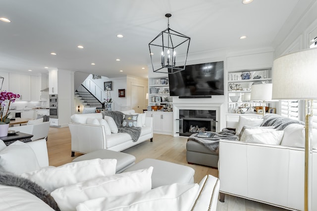 living room with a chandelier, light hardwood / wood-style flooring, and crown molding