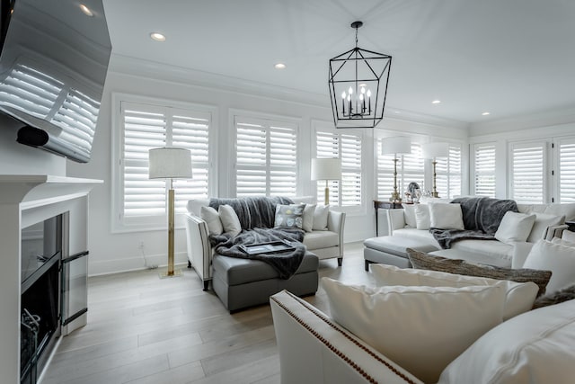 living room featuring light hardwood / wood-style flooring, an inviting chandelier, and ornamental molding