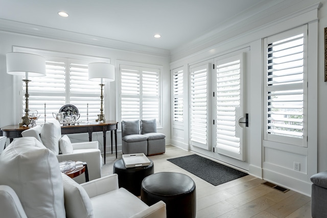 living room with ornamental molding, a healthy amount of sunlight, and light hardwood / wood-style floors