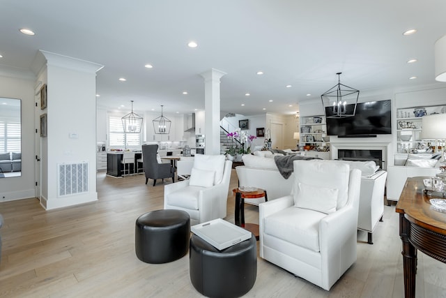 living room featuring a chandelier, ornamental molding, and light wood-type flooring