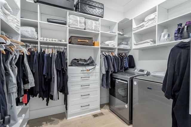 spacious closet featuring light hardwood / wood-style floors and independent washer and dryer