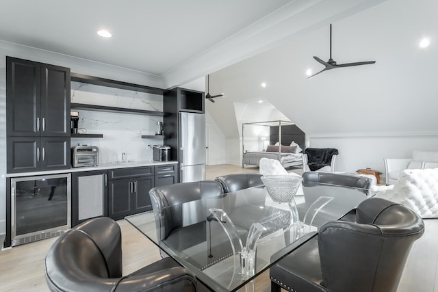 dining area featuring lofted ceiling, crown molding, ceiling fan, light hardwood / wood-style floors, and beverage cooler