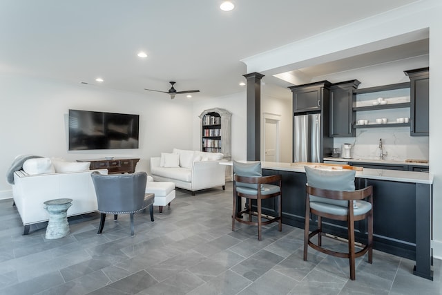 kitchen featuring a breakfast bar, stainless steel fridge, sink, and ceiling fan