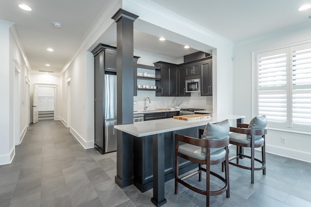 kitchen featuring ornamental molding, sink, appliances with stainless steel finishes, and a breakfast bar area