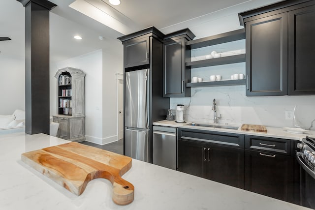 kitchen featuring decorative backsplash, stainless steel appliances, light stone counters, and sink