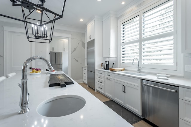 kitchen with decorative light fixtures, stainless steel appliances, white cabinetry, and sink