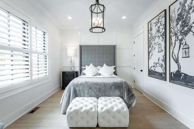 bedroom featuring a notable chandelier, crown molding, and light hardwood / wood-style flooring