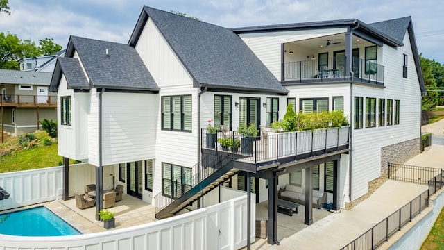 back of property featuring a patio, a balcony, ceiling fan, and a fenced in pool