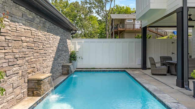 view of swimming pool with pool water feature and a patio