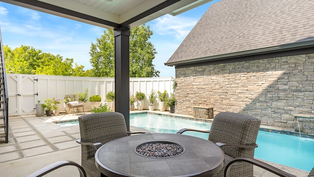 view of patio / terrace with pool water feature, a fenced in pool, and a fire pit