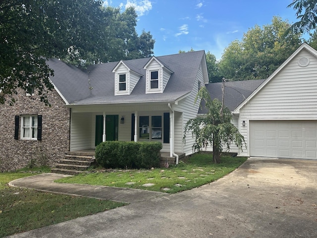 new england style home with covered porch, a front yard, and a garage