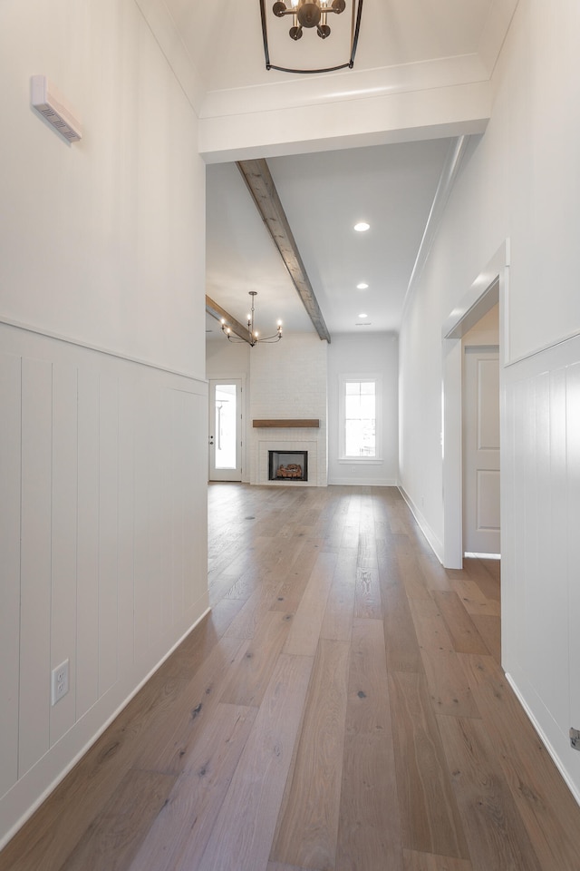 unfurnished living room featuring ornamental molding, hardwood / wood-style floors, beam ceiling, and a large fireplace