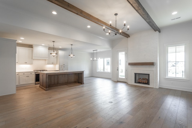 kitchen featuring beam ceiling, white cabinets, hardwood / wood-style floors, and a spacious island