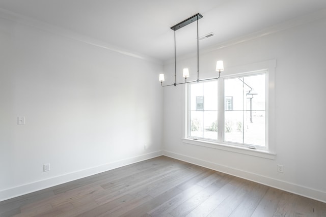 unfurnished room featuring a notable chandelier, crown molding, and hardwood / wood-style flooring