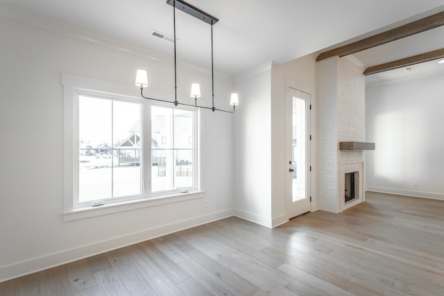 entrance foyer with a brick fireplace, ornamental molding, a notable chandelier, and light hardwood / wood-style floors