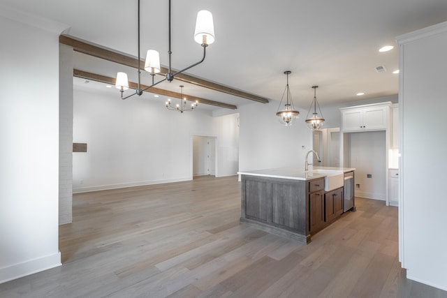 kitchen featuring white cabinets, hanging light fixtures, sink, a center island with sink, and light wood-type flooring