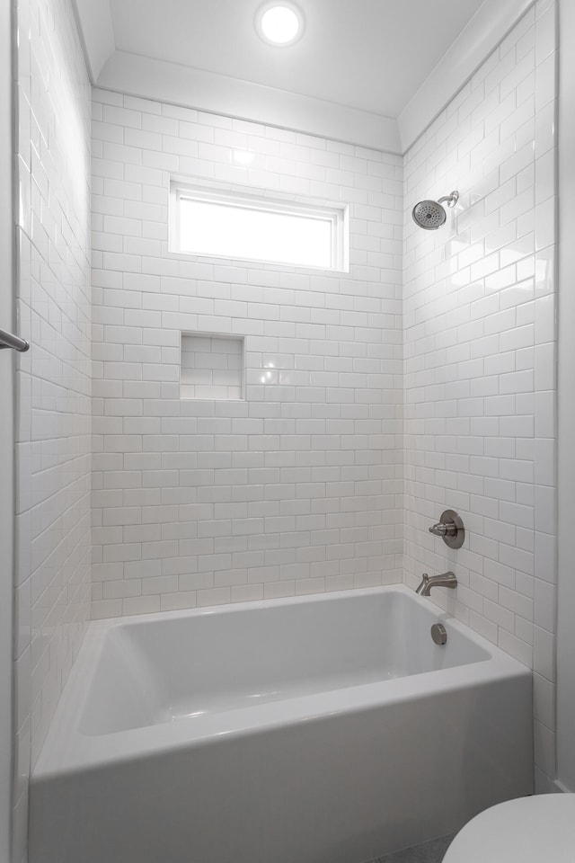 bathroom with toilet and tiled shower / bath