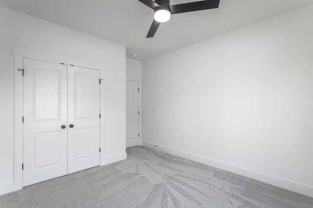 unfurnished bedroom with ceiling fan, light colored carpet, and a closet