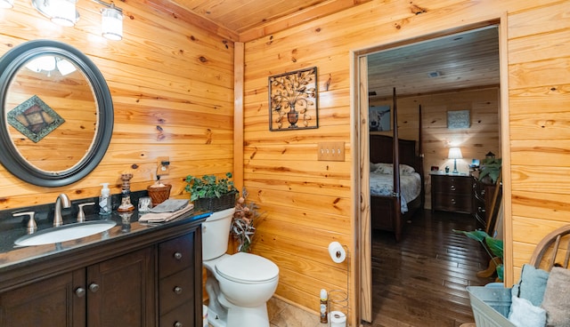 bathroom featuring wooden walls, wooden ceiling, hardwood / wood-style floors, toilet, and vanity