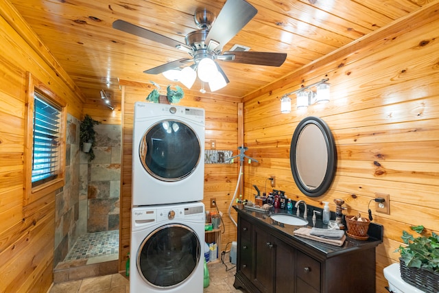 washroom featuring wooden walls, wood ceiling, sink, ceiling fan, and stacked washer / drying machine