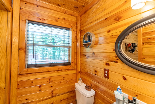 bathroom featuring toilet and wood walls