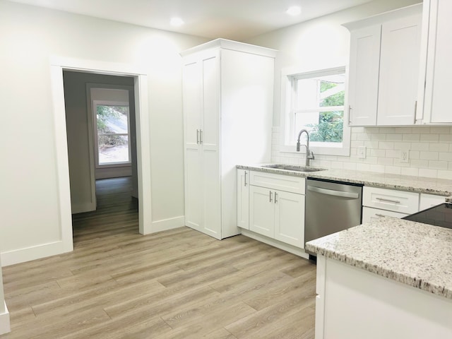 kitchen featuring light hardwood / wood-style flooring, white cabinetry, sink, tasteful backsplash, and stainless steel dishwasher