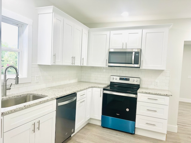 kitchen with light wood-type flooring, white cabinets, stainless steel appliances, and sink