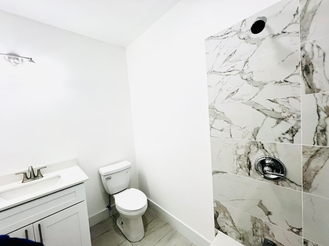 bathroom featuring toilet, a tile shower, and vanity