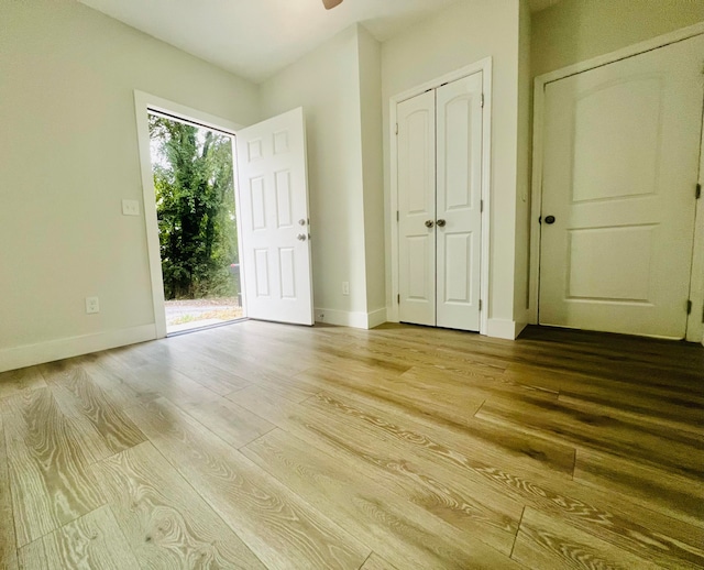 unfurnished bedroom with a closet, ceiling fan, hardwood / wood-style flooring, and access to exterior