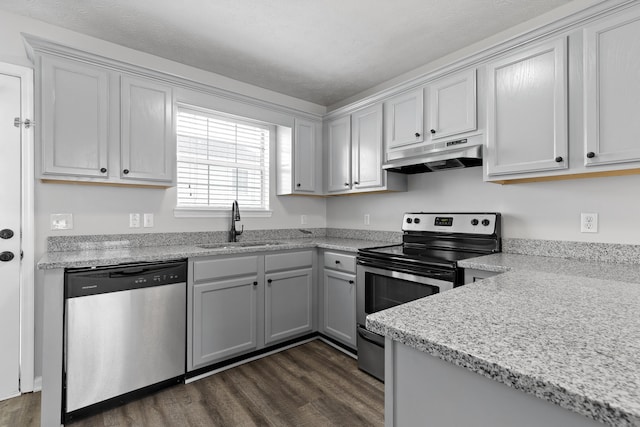 kitchen with stainless steel appliances, sink, dark hardwood / wood-style floors, and light stone countertops