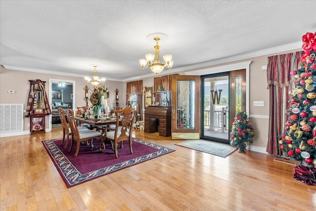 dining space with ornamental molding, a textured ceiling, light hardwood / wood-style flooring, and an inviting chandelier