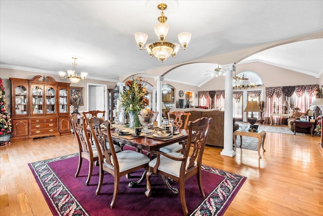 dining room featuring lofted ceiling, light wood-type flooring, and ornate columns