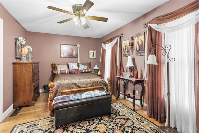 bedroom with ceiling fan, light wood-type flooring, and multiple windows