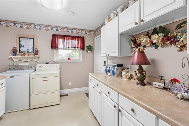 clothes washing area featuring cabinets and washer and clothes dryer