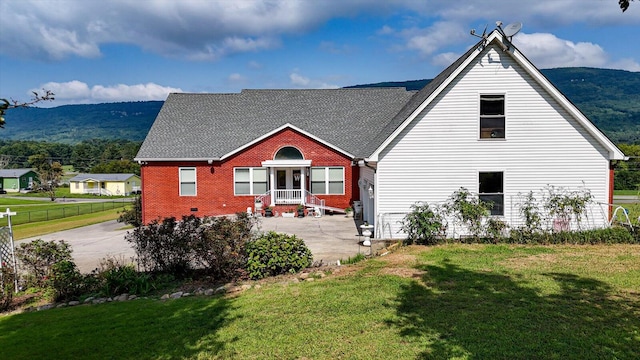 back of property featuring a mountain view and a lawn