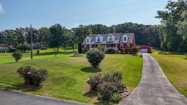 cape cod-style house with a garage, a front yard, and an outbuilding