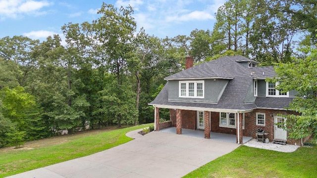 view of front of house with stucco siding, entry steps, a front lawn, a shingled roof, and brick siding