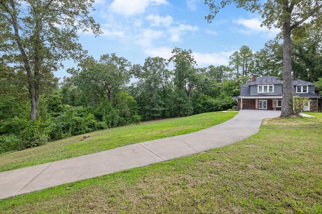 view of front of home featuring brick siding, a chimney, concrete driveway, and a front yard