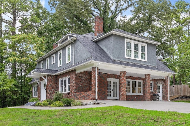 view of front of property with stucco siding, fence, a front yard, brick siding, and a chimney