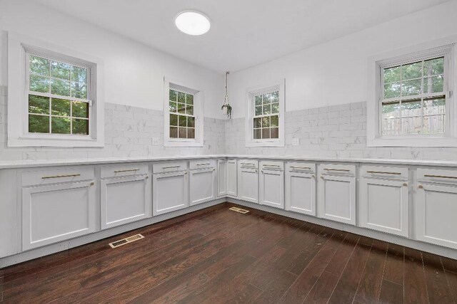 kitchen with light countertops, dark wood-style floors, tasteful backsplash, and visible vents